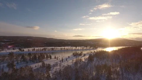 Slow flight over snow covered landscape against the sun, Norway Stock Footage 74602796