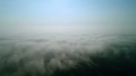 A slow flight over white thick clouds. The horizon divides the blue sky. Video stock 215121686