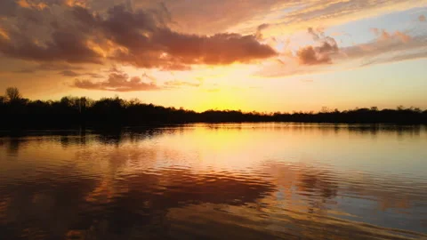 Slow flight at sunset over golden lake Stock Footage 149280806