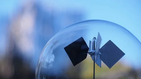 Slow fluid relaxing motion of radiometer against a blue sky and green background Stock Footage 94840008