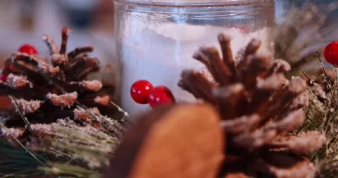 Slow focus shift across pinecones red berries and festive candle decor Stock Footage 340277983