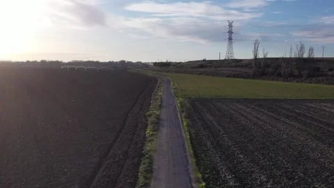 Slow Forward Drone Flight Over Rural Road Between Green and Plowed Fields Stock Footage 325223162