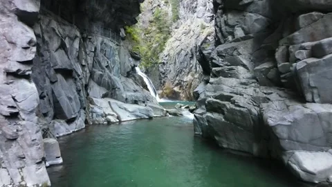 Slow forward flight through rocky gorge toward waterfall Stock Footage 331900715