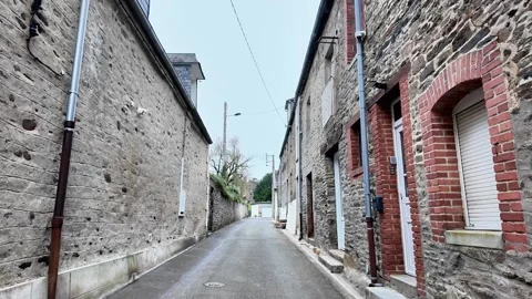 Slow forward moving shot through a narrow alley lined with rustic stone houses u Stockbeeldmateriaal 332679569