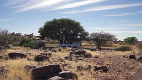 Slow ground-level pan of an overland truck with open rooftop tents under a tree 스톡 동영상 347912673