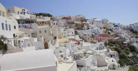 Slow hand held pan across beautiful Cliffside buildings in Santorini, Greece￼ Stock Footage 202253890