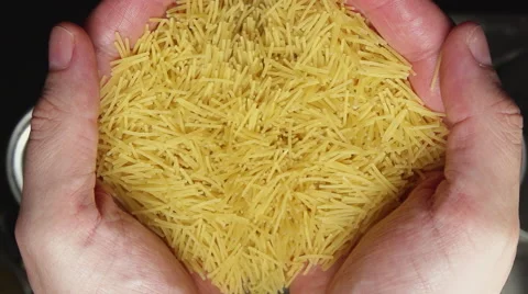 SLOW: Hands throw a small noodles in a steel pan (top view) 動画素材 64416794