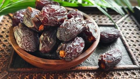 Slow horizontal camera move across date fruit in wooden bowl with palm leaf.. Stock Footage 339080878