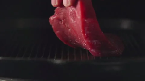 SLOW: Human hand puts a steak of meat on a grill 動画素材 62611324