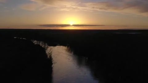 Slow Lateral Drone Flight Over Wide River with Golden Reflections at Sunset Stock Footage 325330906