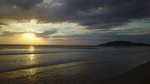 Slow low flight at sunset with surfers, SUP and sailboats on the horizon Stock Footage 91014187
