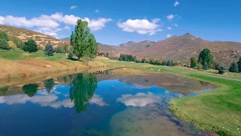 Slow low pan over pond to rise over fairway to lower into players Stock-Footage 105607982