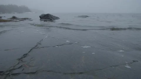 Slow low tracking out shot of water lapping over rocks at edge of a lake Stock Footage 146288890