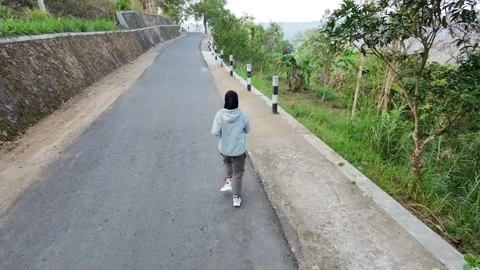 Slow mo back view of hijab woman jogging on empty rural road. Stock Footage 342334884
