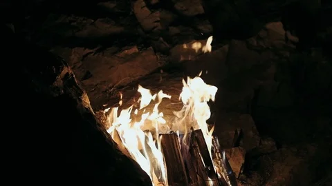 Slow mo bonfire in the camp. Reflection of fire on the cave stones. Stock Footage 98643426