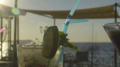Slow mo of cocktail on a bar with sunset in the background Stock Footage 140052472