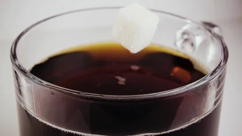 Slow mo. A cube of sugar falls into a glass with a drink Stock Footage 75675950