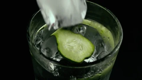 Slow mo. Cucumber and ice drops into a glass with cucumber water Video stock 75715278