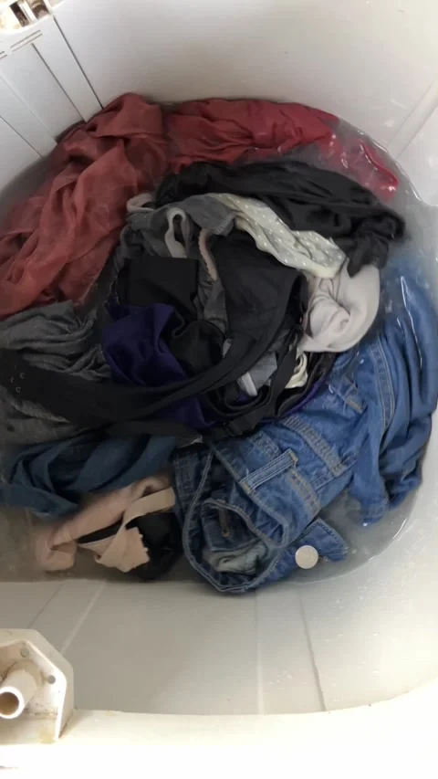 Slow mo dirty clothes soaking and spinning inside top load washing machine. Stock Footage 344996295