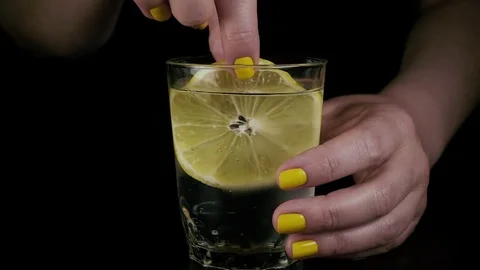 Slow mo. A female hand is dipping a lemon in a glass Stock Footage 76155981