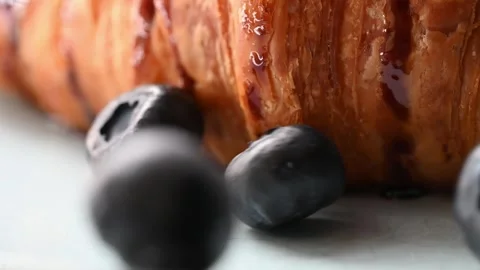 Slow-mo footage of berries falling onto a plate with a croissant 스톡 동영상 255949336