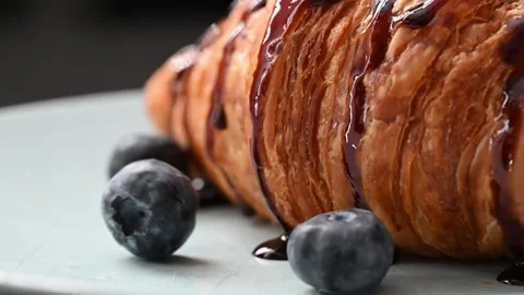 Slow-mo footage of berries falling onto a plate with a croissant Vídeo Stock 255949337