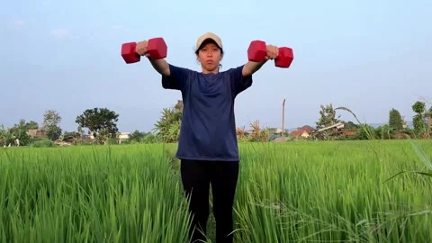 Slow mo front view woman doing dumbbell lateral raise in green grass field. Vídeo Stock 342334730