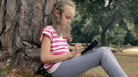 Slow-Mo: Girl Leaning On Tree Playing With Touch Pad Stock Footage 35297415