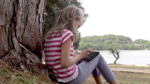 Slow-Mo: Girl Leaning On Tree Playing With Touch Pad Stock Footage 35297423