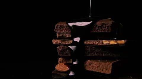 Slow mo. Liquid dark chocolate is poured onto a pile of chocolate Video stock 75186897