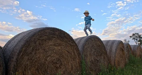 Slow-Mo Little Boy Jumping On Bale Of Hay Stock Footage 90879728