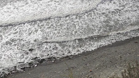 Slow mo long foamy waves on a stony shore Stock Footage 81402126