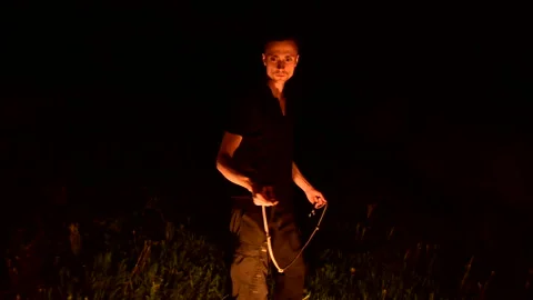 Slow-mo of man in dark rotates burning torch. Low key. Fire show. Close-up. Stock Footage 121496889