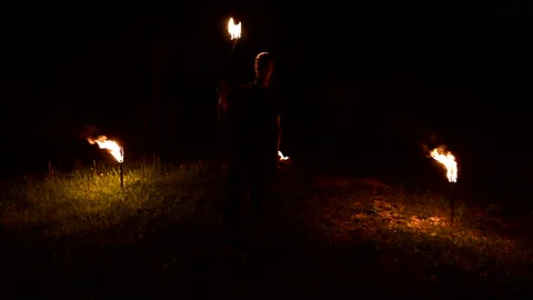 Slow-mo of man in dark rotates burning torch. Low key. Fire show. Close-up. Stock Footage 123420184