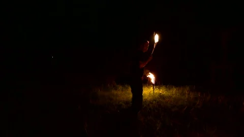Slow-mo of man in dark rotates burning ball poi. Low key. Fire show. Close-up. Stock Footage 124529753
