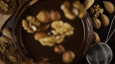 Slow mo. A mixture of nuts falls down into chocolate Stock Footage 74732738