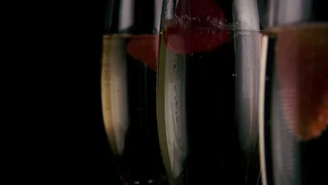 Slow mo. In one of the three glasses with champagne falls strawberries Stock-Footage 75951682