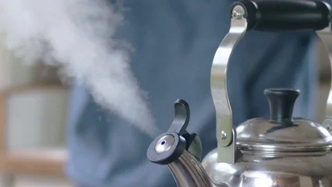 Slow-mo shot of steam flowing out of teapot as young hispanic man picks it up Stock Footage 84477709