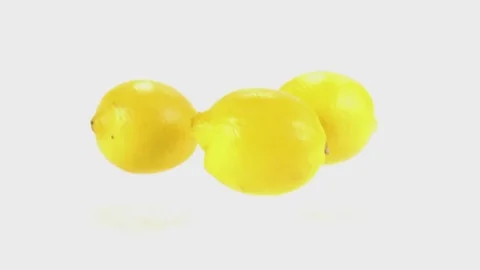 Slow mo shot of three lemons falling in slow motion onto a white cyc Stock Footage 70681351