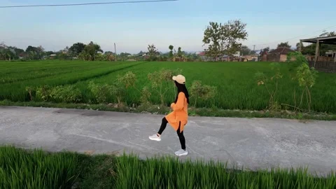 Slow mo side view of hijabi woman jogging on rural road by rice field. 스톡 동영상 341835271