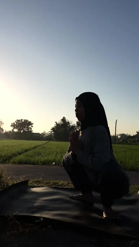 Slow mo silhouette of hijabi doing malasana yoga squat by a rice field  Stock Footage 340448337