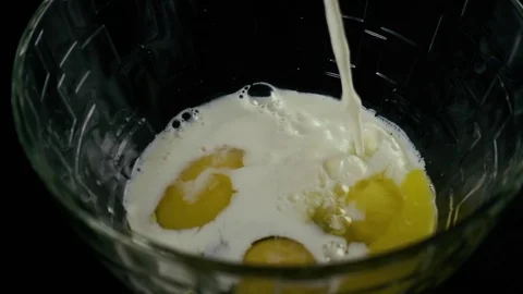Slow mo. Three broken eggs flowing milk Stock Footage 75534230