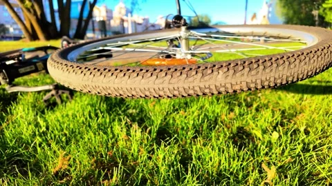 Slow-Mo Tracking Shot: Spinning Wheel of Fallen Bicycle in Grass Stock Footage 308178404