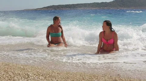 Slow mo Two Beautiful Girl enjoying the sun and sea lies on the coast Stock Footage