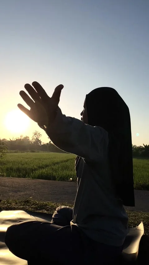 Slow mo vertical silhouette of hijabi woman doing upward yoga stretch at sunrise 動画素材 340447649