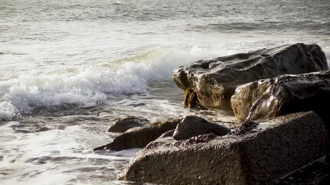 Slow mo wave breaks down on concrete and stones Stock Footage 82355996