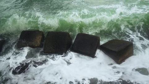 Slow mo the wave is broken against the square stones of a breakwater Stock Footage 82027532