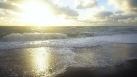 Slow mo the wave crashes into the shore in the setting sun Stock Footage 82318839