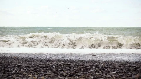 Slow mo the wave is powerfully breaking about the pebble beach Stock Footage 82656109