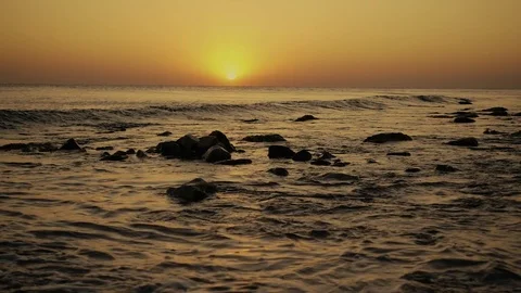 Slow mo the wave rolls over a stony shore at sunset Stock Footage 81175901